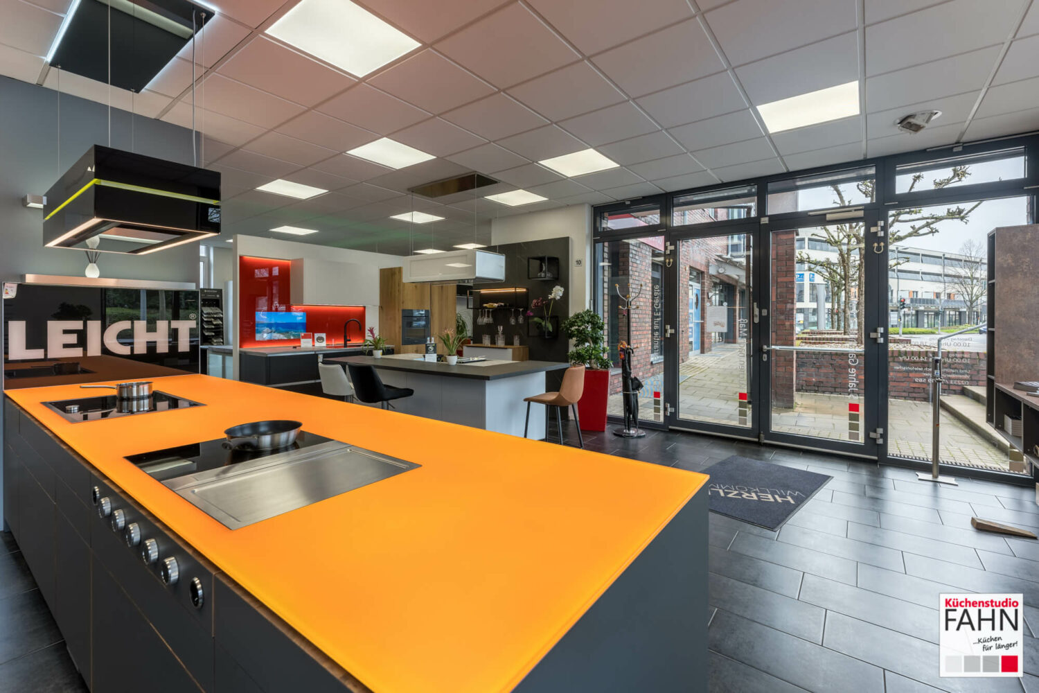 Leicht Inselküche Designküche mit orangener Glas Arbeitsplatte